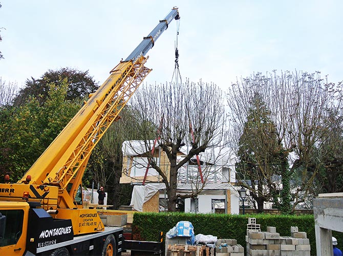 France-Maisons-idf. Nos réalisations. La grue charge derrière les arbres